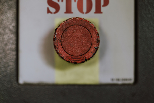 Close up photo of a worn industrial stop button. Button itself is in sharp focus to draw maximum attention - except hero/header image for safety training materials.