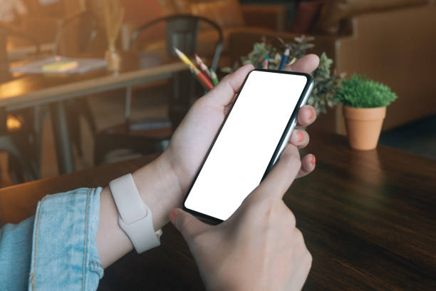 istock Woman using smartphone at abstract blurred coffee. Blank screen for graphics display montage. 1125235241