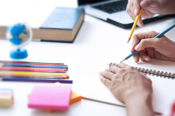 istock Two students doing homework and helping each other sitting in a table at class room 1125271202