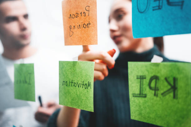 istock Team of male and female project managers discussing ideas while collaborating on project sharing creative solution standing behind glass wall with sticky notes. Coworkers having business meeting 1125277898