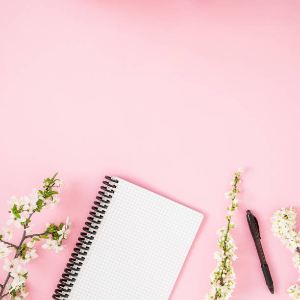 istock Floral frame with white spring flowers and notebook on pink background. Flat lay, top view. Spring time concept. 1125279298