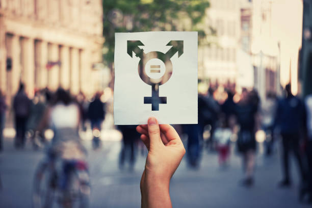 transgender symbol Hand holding a paper sheet with transgender symbol and equal sign inside. Equality between genders concept over a crowded city street background. Sex rights as a metaphor of social issue. transgender person photos stock pictures, royalty-free photos & images