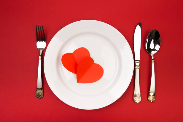 istock Festive table setting for Valentine's Day with fork, knife,  hearts on a red background. Top view. - Image 1125289489