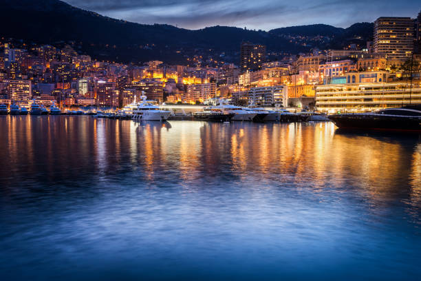 Monaco Evening Skyline Monaco evening skyline, city lights with reflection in Mediterranean Sea bay, southern Europe. monte carlo photos stock pictures, royalty-free photos & images