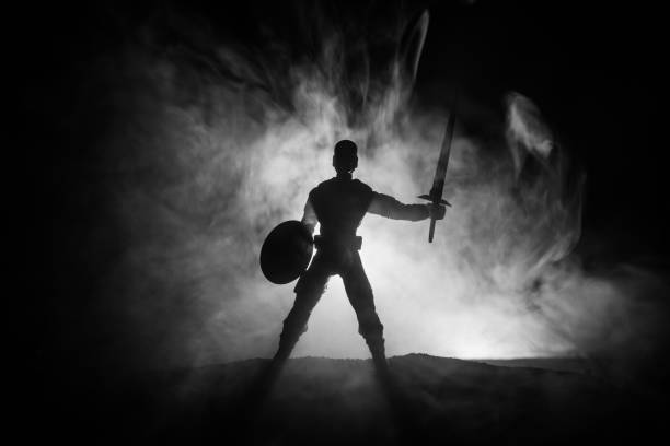 istock Medieval battle scene. Silhouettes of figures as separate objects, fight between warriors on dark toned foggy background. Night scene. 1125291797