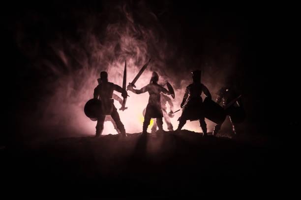 istock Medieval battle scene. Silhouettes of figures as separate objects, fight between warriors on dark toned foggy background. Night scene. 1125291832
