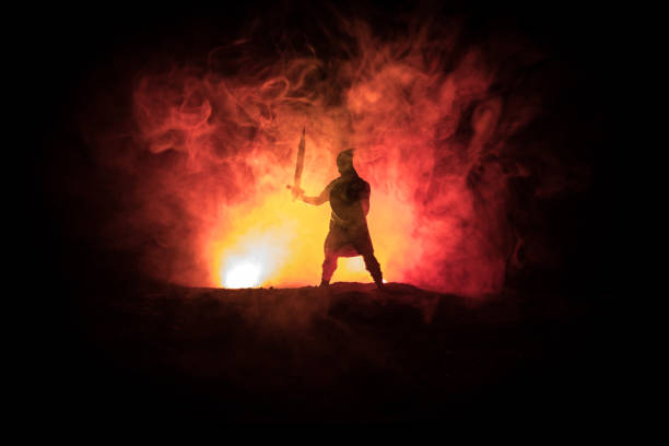istock Medieval battle scene. Silhouettes of figures as separate objects, fight between warriors on dark toned foggy background. Night scene. 1125291833