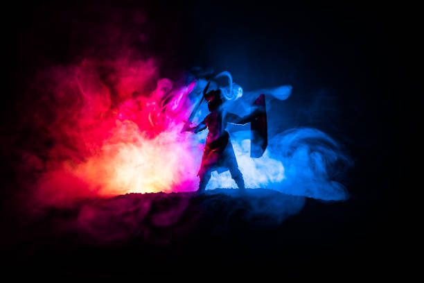 istock Medieval battle scene. Silhouettes of figures as separate objects, fight between warriors on dark toned foggy background. Night scene. 1125291858