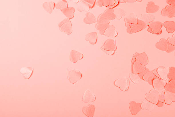 Coral background with heart-shaped confetti.