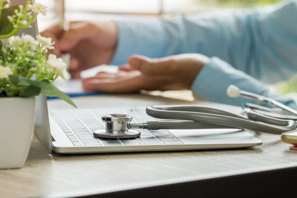 mão de médico de medicina explicando para o paciente no quarto, de consultoria, trabalhando no computador portátil na mesa na clínica, um estetoscópio de foco na tabela de primeiro plano no hostpital. conceito de saúde e médico. - hostpital - fotografias e filmes do acervo