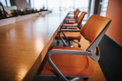 Close up of orange chair in a board room without people.