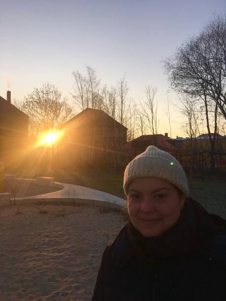 Lady portrait with a winter sunrise behind her. The sun is passing through some neighborhood houses.