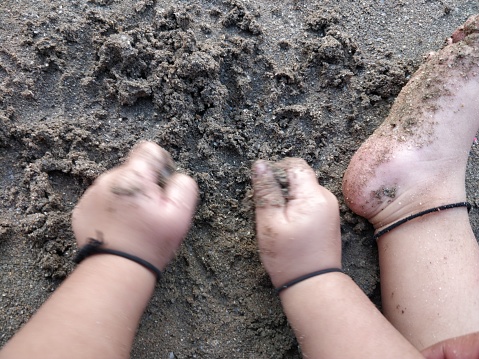 A child's feet with mud. Having waded through the mud, he stands in lush green grass.