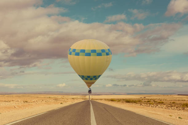 Hot air balloon over desert and long road