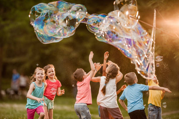 istock Group of children playing with rainbow bubbles in nature. 1125311031