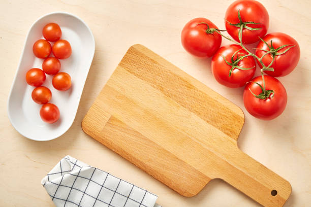 istock Raw tomato on table with chopping board and textile napkin. 1125312373