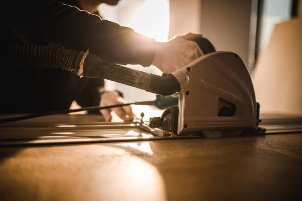 istock Unrecognizable carpenter cutting wood plank with electric saw. 1125314718