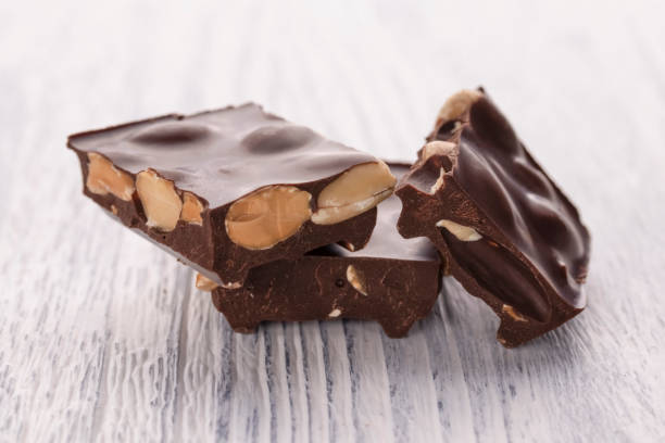 istock Slices of dark chocolate with nuts on a white wooden table 1125317064