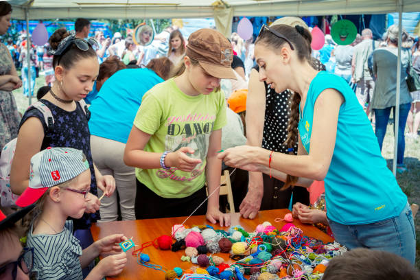 Young woman – volunteer explaining how to knit colorful table napkin stock photo