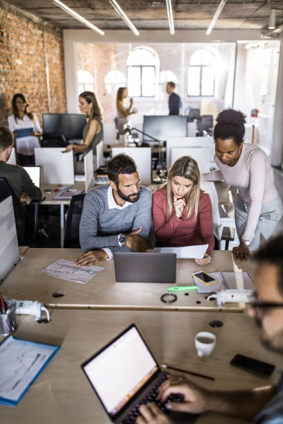 istock Group of business people cooperating while analyzing reports at corporate office. 1125318143