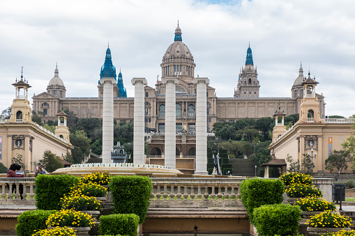 People walking next to the Four Columns, Magic Fountain and Palace of Montjuic at Barcelona city, Spain.