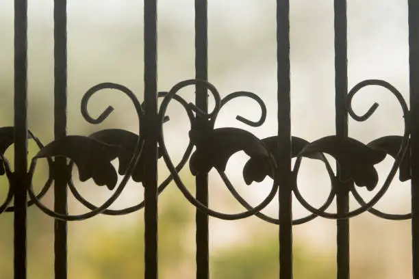 Photo of Close up detail of overlapping cast-iron decorations of a balcony door with strong bokeh effect.