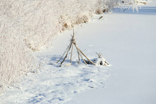 istock Teepee shape made of dead branches on a frozen river bank 1125348168