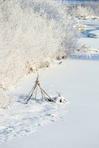istock Teepee shape made of dead branches on a frozen river bank 1125348174