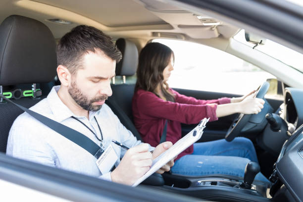 istock Car Coach Writing On Clipboard While Woman Driving Car 1125350121