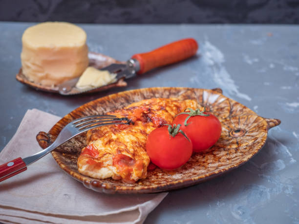 Breakfast with scrambled eggs and cheese. Cutlery on a gray wooden background.