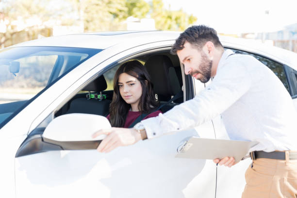istock Teacher Adjusting Car Mirror For Woman During Driving Class 1125352767