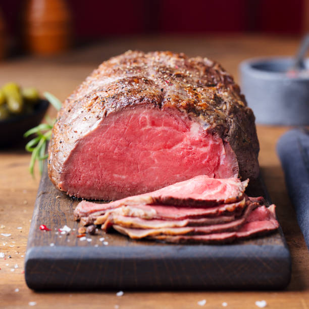 Roast beef on cutting board. Wooden background. Close up