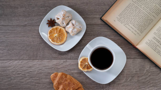 Cup of coffee with book on wooden table