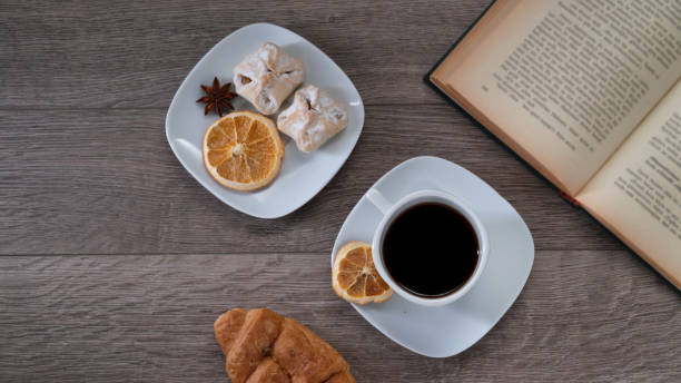 Cup of coffee with book on wooden table