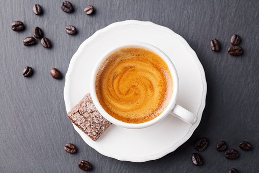 Coffee espresso in white cup on black slate background. Top view