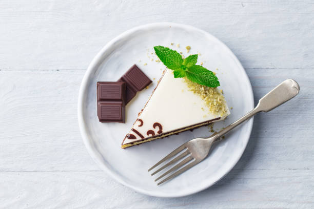 White chocolate cake with fresh mint leaf on a plate. Wooden background. Top view.