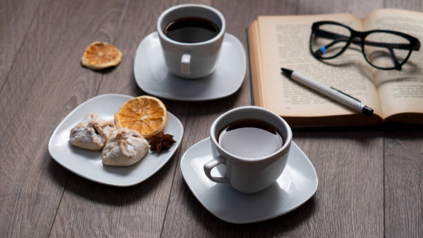 Cup of coffee with book on wooden table