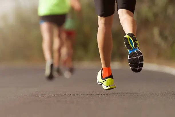 Runners feet running on road close up on shoe, male triathlete runner