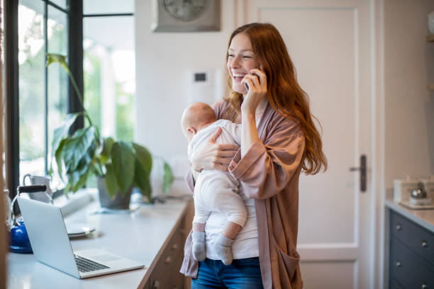 istock Woman talking on mobile phone carrying baby boy 1125359664