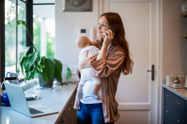 istock Mother talking on mobile phone carrying baby boy 1125359677