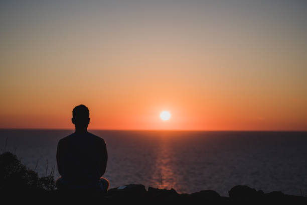 giovane che guarda al tramonto sul mare. concetto di divertimento e relax, pieno di esperienze indimenticabili da ricaricare. bilancia mente e corpo - sunset yoga young men caucasian foto e immagini stock