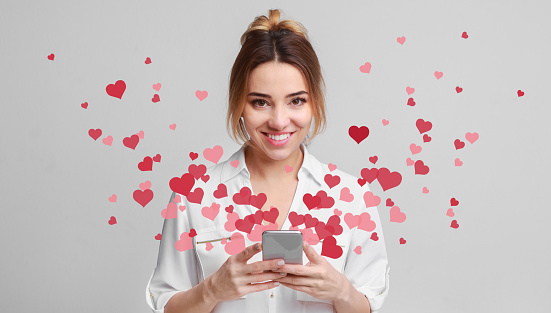 Valentine day concept, love message - hearts flying out smartphone in womans hands