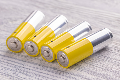 AA batteries lie on an old white wooden table. The concept of vital energy reserve