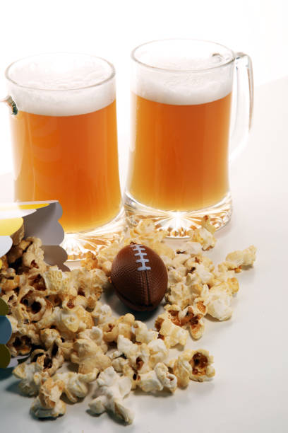istock popcorn, football and Beer on a table. Great for Bowl Game 1125376902