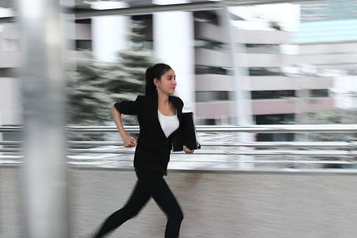 Abstract blurred motion of young Asian business woman running to work.