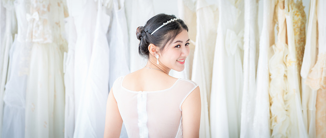 Young asian beautiful bride woman standing smiling with wedding dress in room with happiness