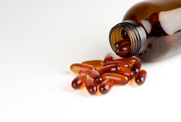 close-up view of orange pills or lecithin capsules in a brown glass bottle on a white background with space for text - lecithin capsule vitamin pill brown imagens e fotografias de stock