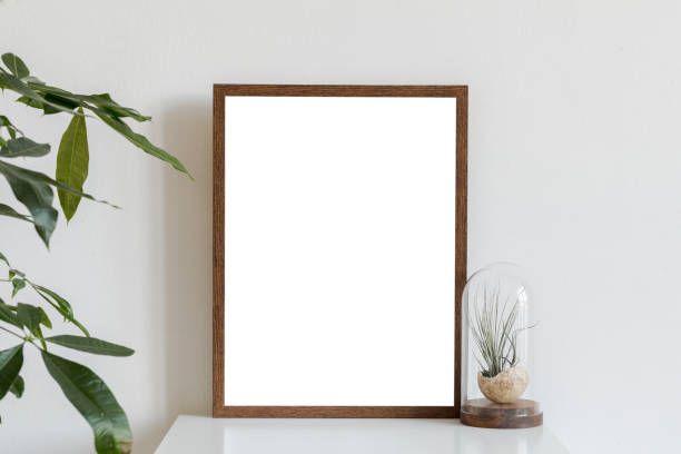 istock Scandinavian and minimalistic interior with brown mock up poster frame on the white shelf with air plants in glass box.White walls. Modern and floral concept. 1125385801