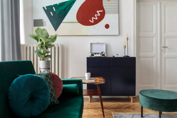 istock Luxury home interior with design velvet sofa, coffee table, pouf, commode and accessroies. White walls with painting. Sunny view. Stylish decor of sitting room. 1125386086
