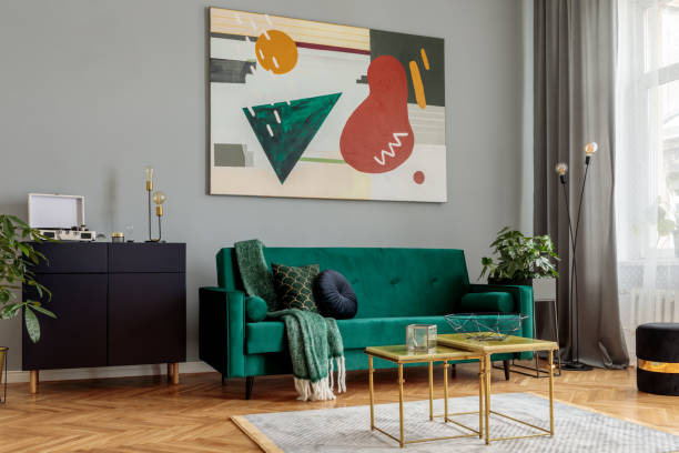 istock Luxury and modern home interior with design green sofa, navy commode, coffee tables, lamp, pouf and accessroies. Abstract painting. Stylish decor of living room with brown parquet. 1125386220